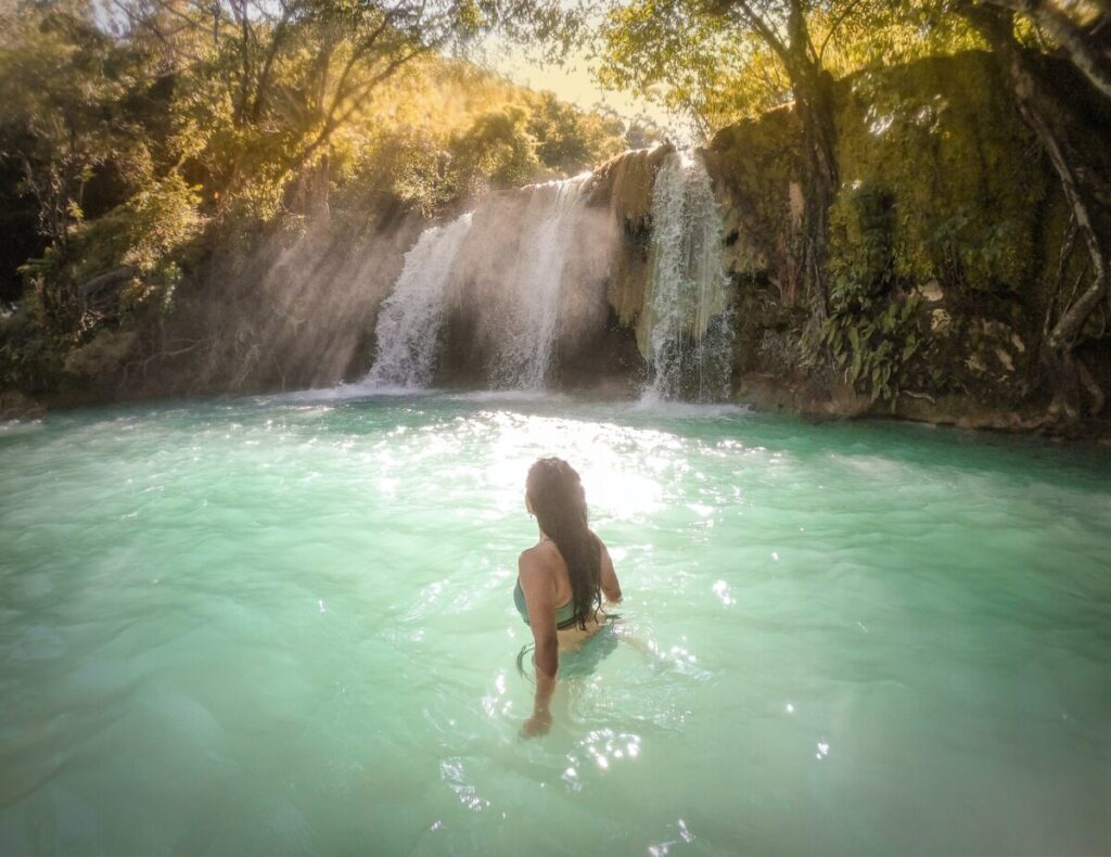 vrouw zwemt bij een waterval
